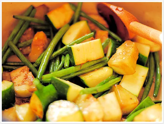 Zugabe von grünen Bohnen, Zucchini und Aubergine zum angebratenen Gemüse für das Ratatouille Rezept