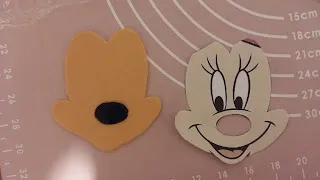 Zusammengesetztes Minnie Maus Gesicht aus hellfarbenem Fondant auf schwarzem Fondant, bereit für weitere Details der Geburtstagstorte.