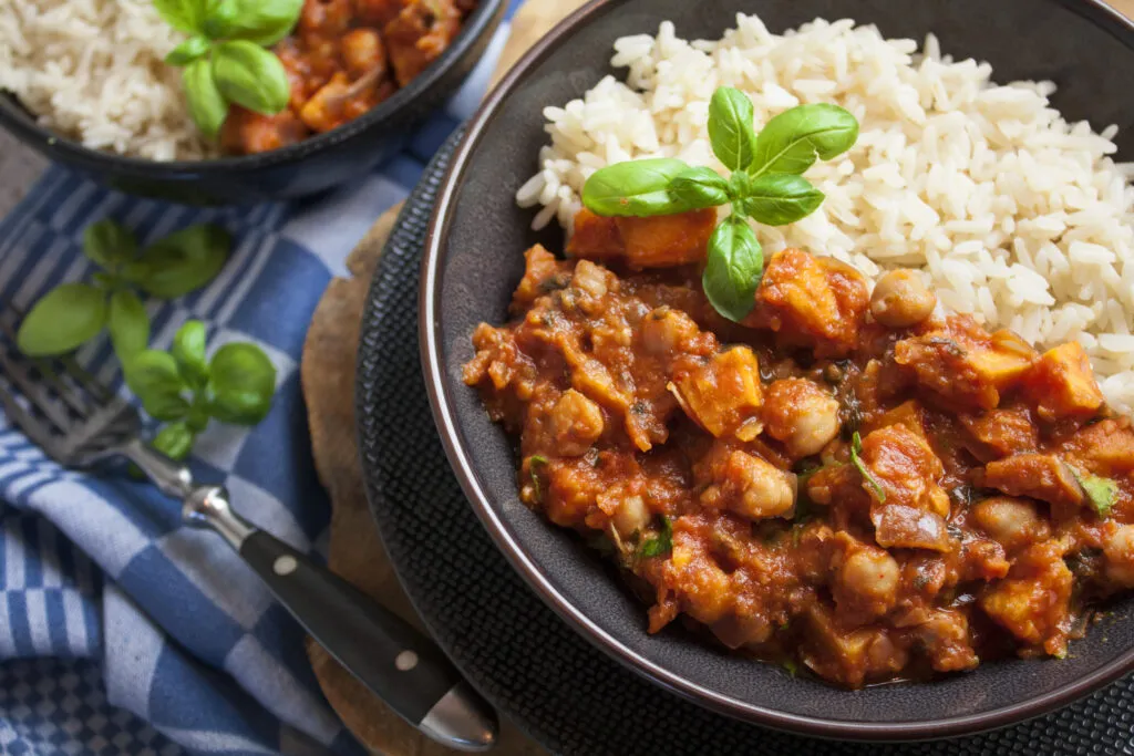 Zutaten für den süßen Kartoffel-Kichererbsen-Eintopf: Süßkartoffeln und Kichererbsen in einem Topf, bereit zum Kochen.