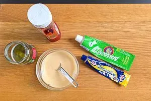 Zutaten für die Burgersauce, darunter Mayonnaise, Senf und Ketchup, werden in einer kleinen Schüssel mit einem Löffel vermischt.