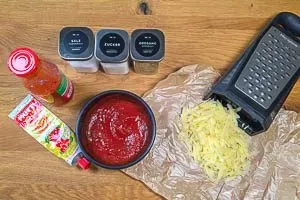 Zutaten für die Tomatensoße verrühren und Käse reiben