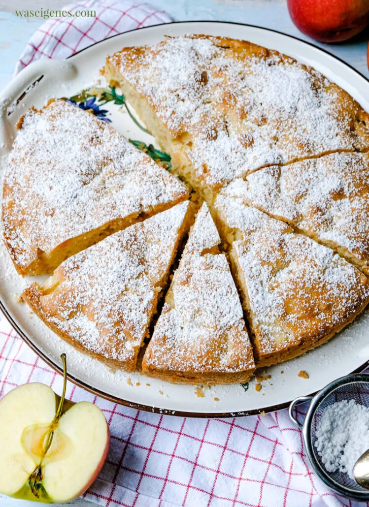 Zutaten für einen schnellen Apfelkuchen: Äpfel, Eier, Butter, Mehl auf einem rustikalen Tisch