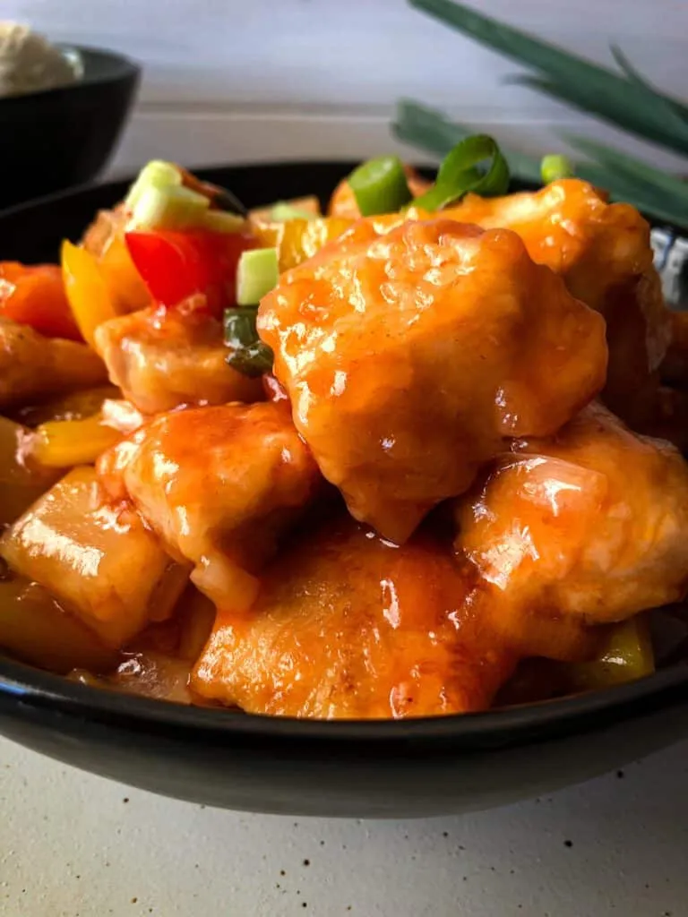 Zutaten für Hähnchen süß-sauer in der Pfanne: goldbraun gebratenes Hühnerfleisch und frisches Gemüse, bereit für die süß-saure Soße.