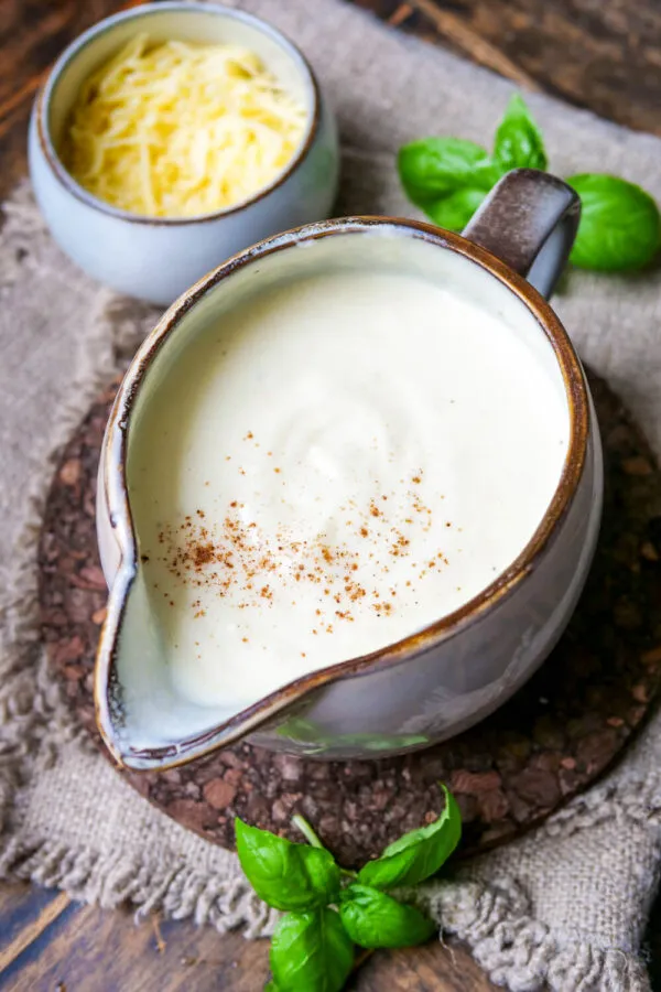 Zutaten für selbstgemachte Käsesoße: geriebener Käse und frische Milch in einer Kanne, bereit für die Zubereitung einer cremigen Käsesoße.