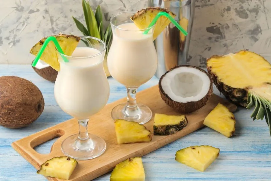 Zwei eisgekühlte Gläser Virgin Colada, dekoriert mit Ananasscheiben und Kokosnussraspeln