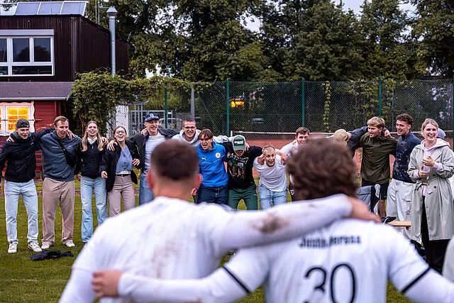 Zwei Fußballspieler und Fans jubeln