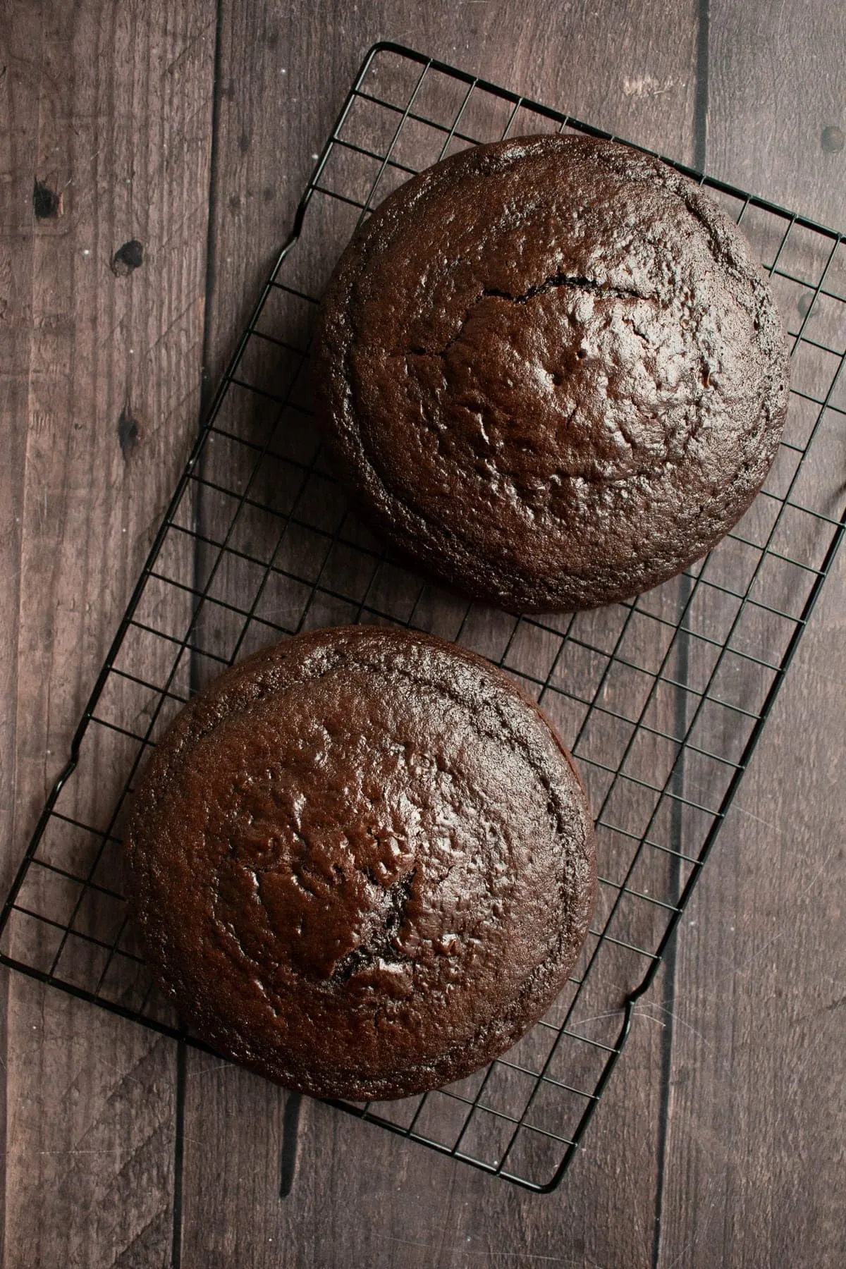 Zwei gebackene Schokoladenkuchen auf einem Drahtkühlgitter auf einem Tisch.