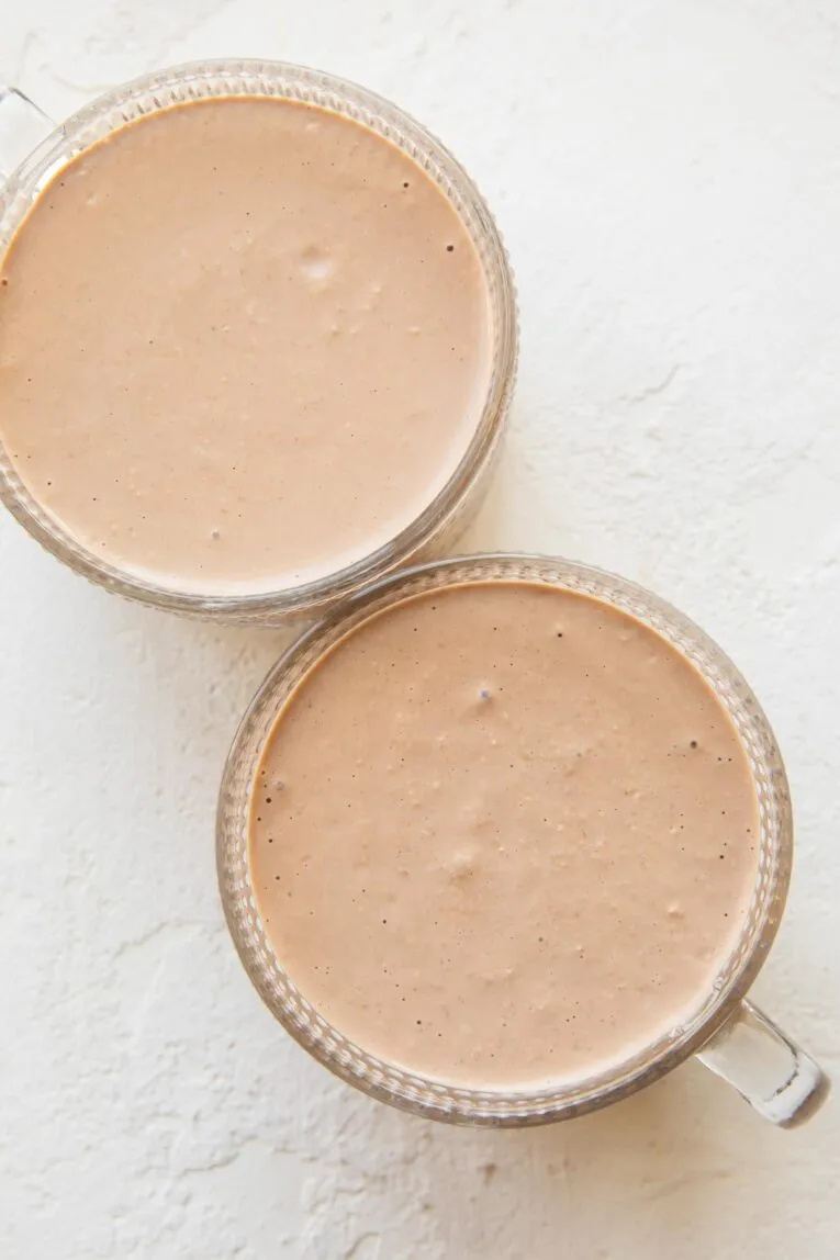 Zwei Gläser mit cremigen Erdnussbutter-Schoko Overnight Oats, bereit für das Topping.