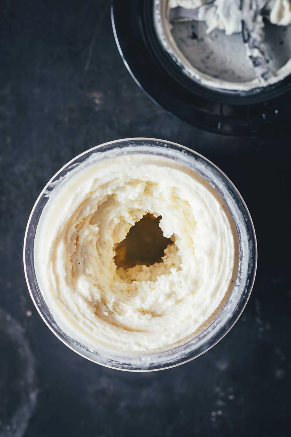 Zwei Gläser mit cremiger Vanilleeis-Portion, verziert mit frischen Früchten, einladend und köstlich.