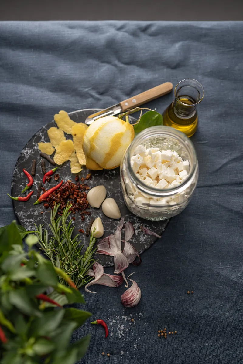 Zwei Gläser mit eingelegtem Schafskäse und Kräutern, perfekt für die deutsche Brotzeit