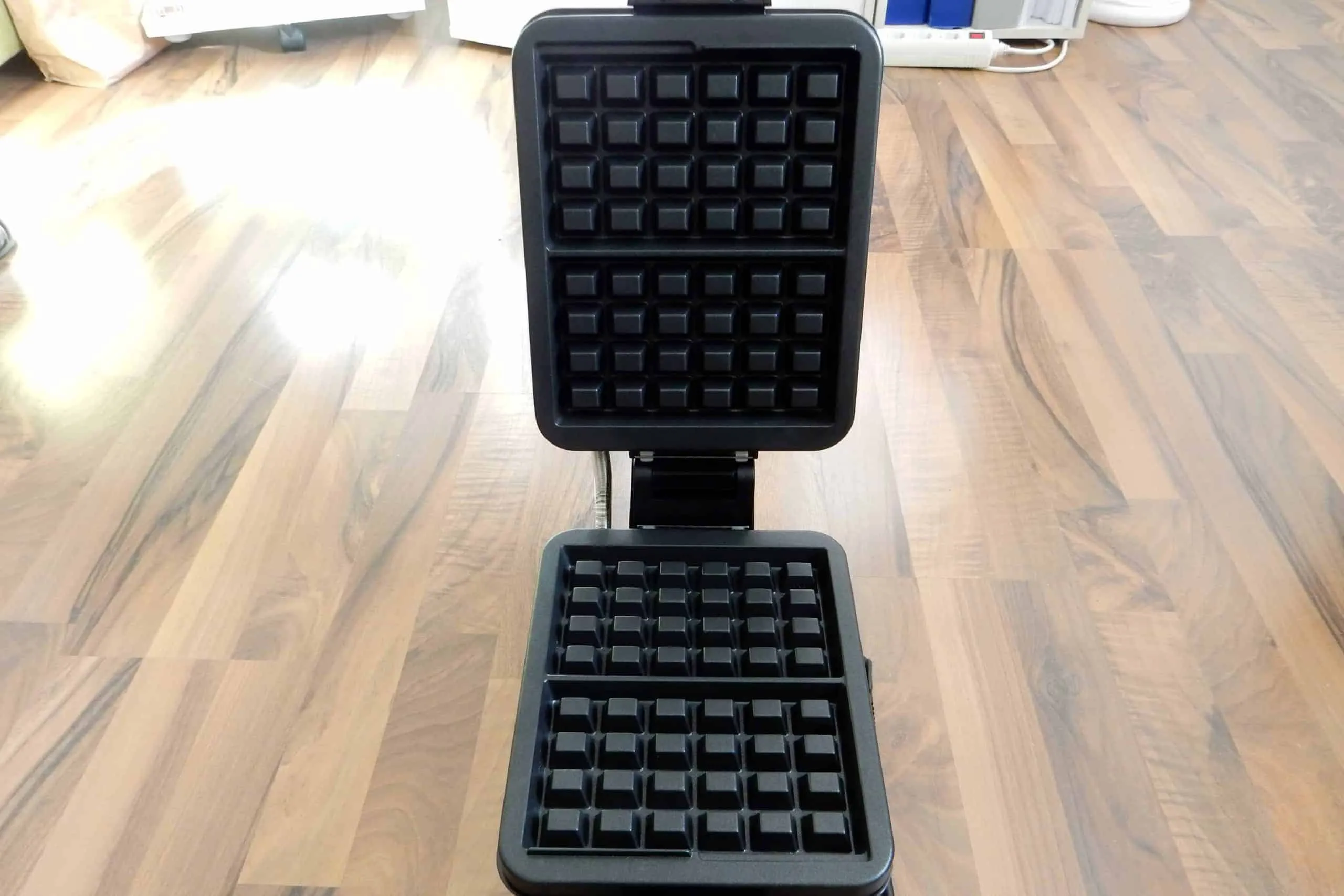 Zwei große, dicke belgische Waffeln, die aus dem Waffelautomaten kommen