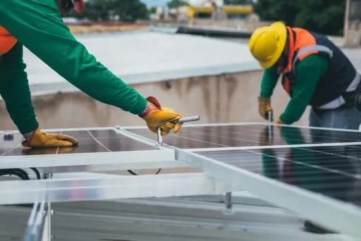 Zwei Handwerker schrauben an einem Solarmodul.