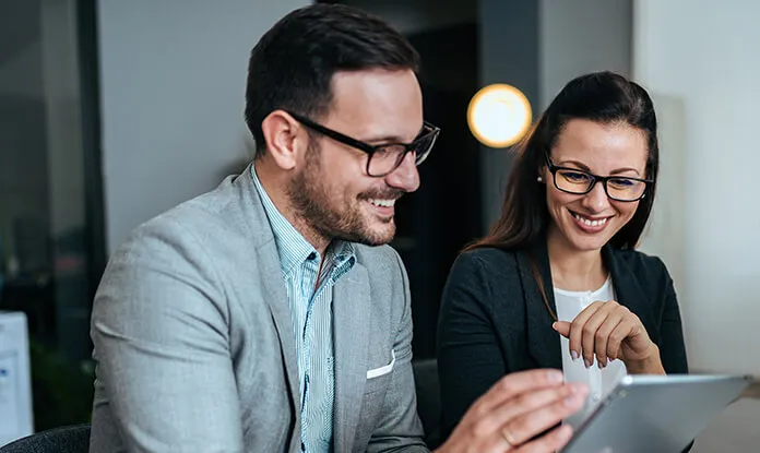 Zwei Kollegen betrachten gemeinsam einen Laptopbildschirm, symbolisierend die Wichtigkeit der Key Person Versicherung der Generali