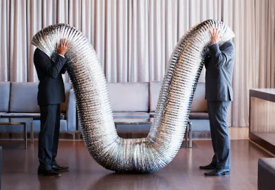 Zwei Kollegen mit Köpfen in einem Schlauch als Bild für ineffektive Kommunikation, unterstreicht die Wichtigkeit sinnvoller Weiterbildung in Kommunikationsfähigkeiten