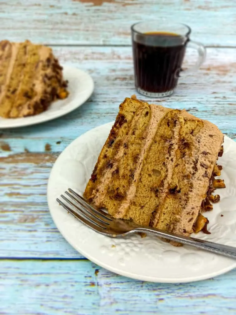 Zwei liebevoll angerichtete Stücke der selbstgemachten Tiramisu Torte auf Desserttellern, begleitet von einer Tasse frischem Kaffee.