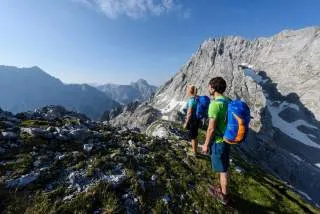 Zwei Menschen beim Wandern mit kleinen Schneefeldern im Hintergrund