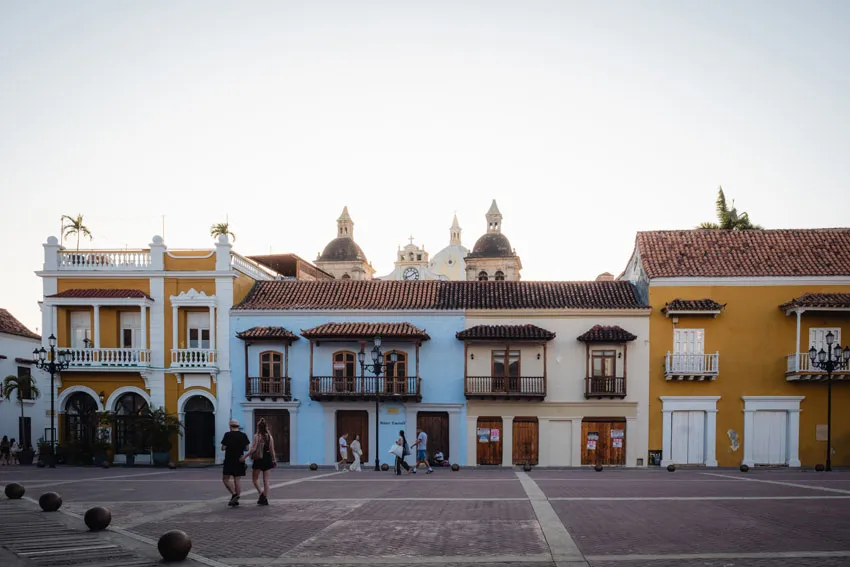 Zwei Menschen spazieren über einen Platz vor bunten historischen Gebäuden