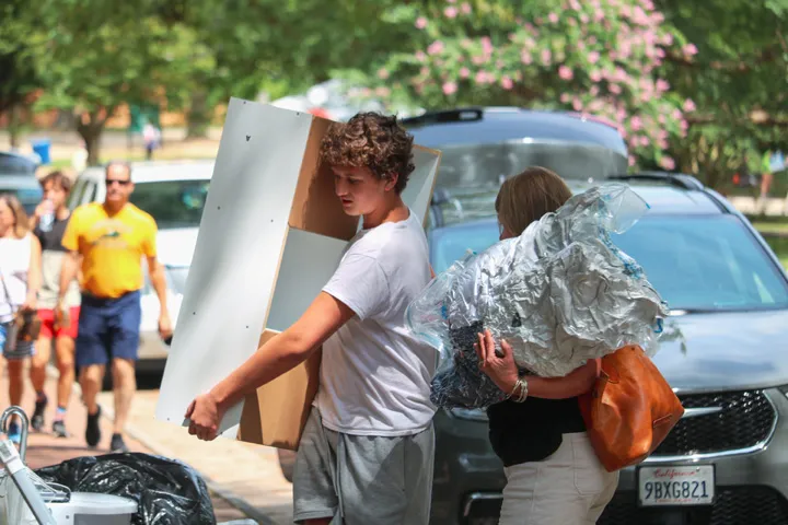 Zwei Personen transportieren große Gegenstände, darunter ein Regal, bereit für neue Anfänge.