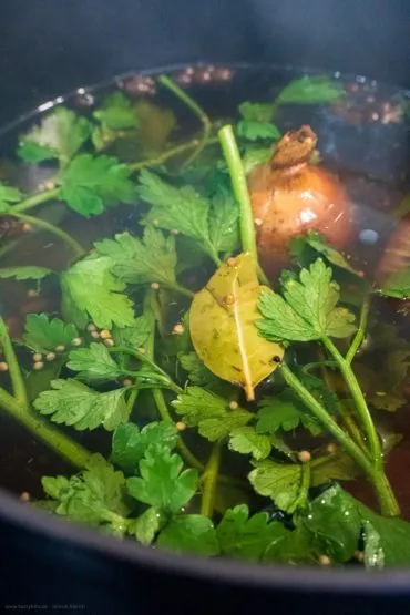 Zwiebelhälften und Gewürze wie Lorbeerblätter und Piment für den Soleier-Sud anrösten