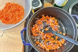 Zwiebeln, Knoblauch, Karotten und Ingwer werden in einem Topf mit Pflanzenöl leicht angedünstet, um Aromen für das rote Linsen Rezept zu entwickeln.
