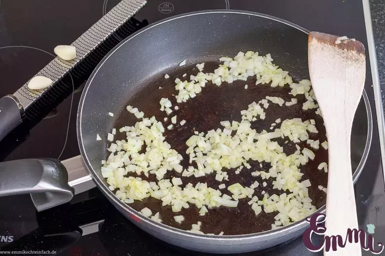 Zwiebeln und Knoblauch in Olivenöl andünsten als Basis für die Zucchinifüllung