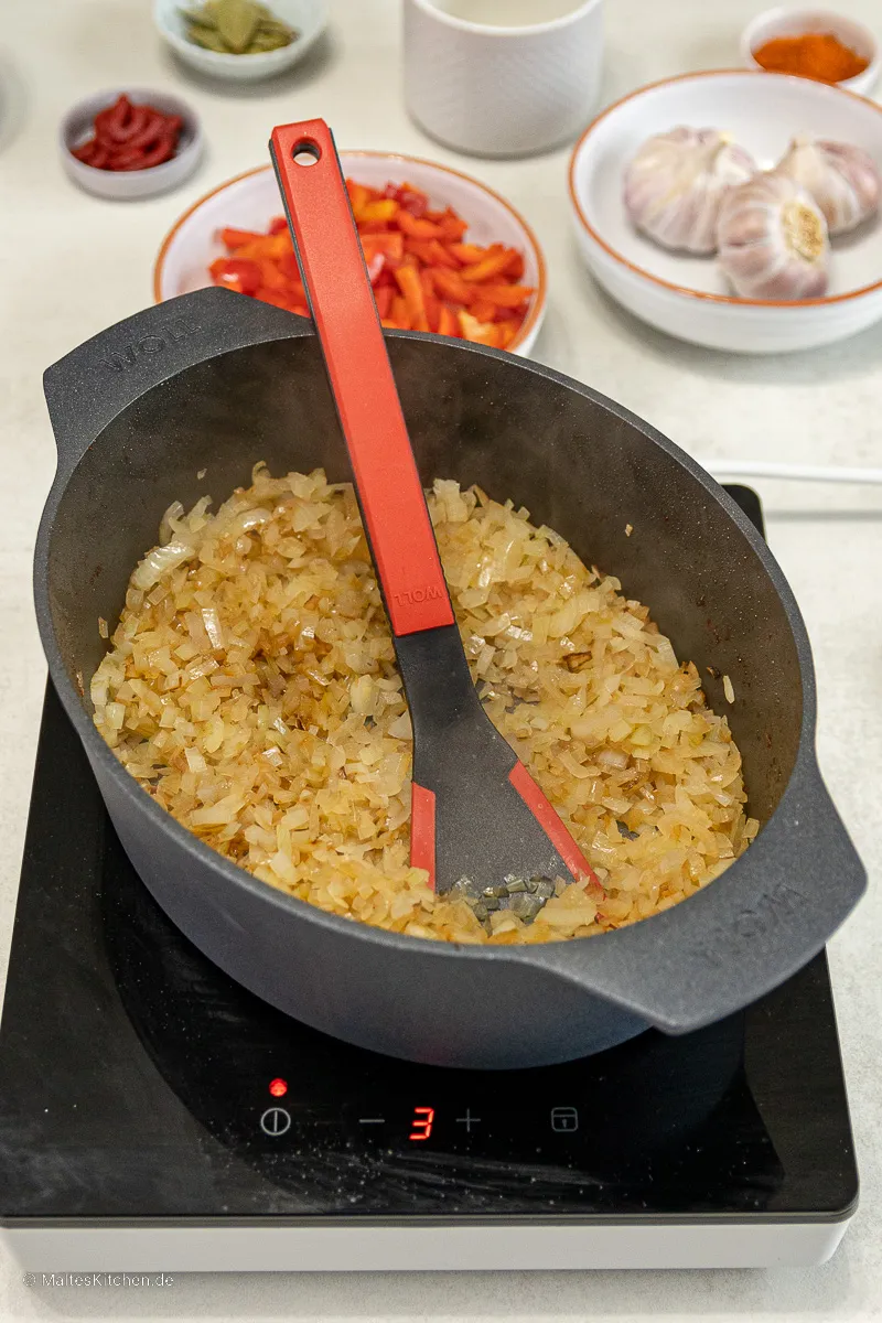 Zwiebeln und Paprika werden im Bräter angeschwitzt, die Basis für eine aromatische Gulaschsauce.