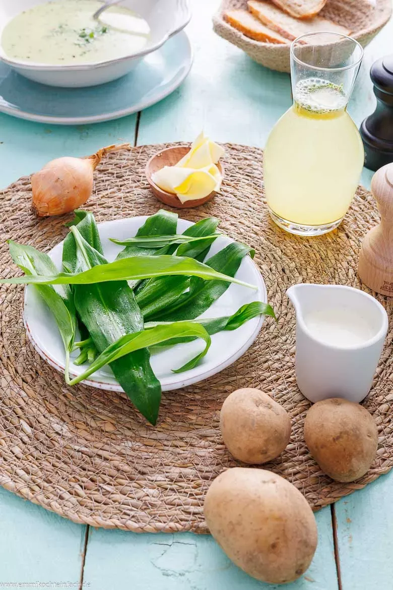 Alle frischen Zutaten für die Bärlauchsuppe übersichtlich auf einem Holztisch präsentiert