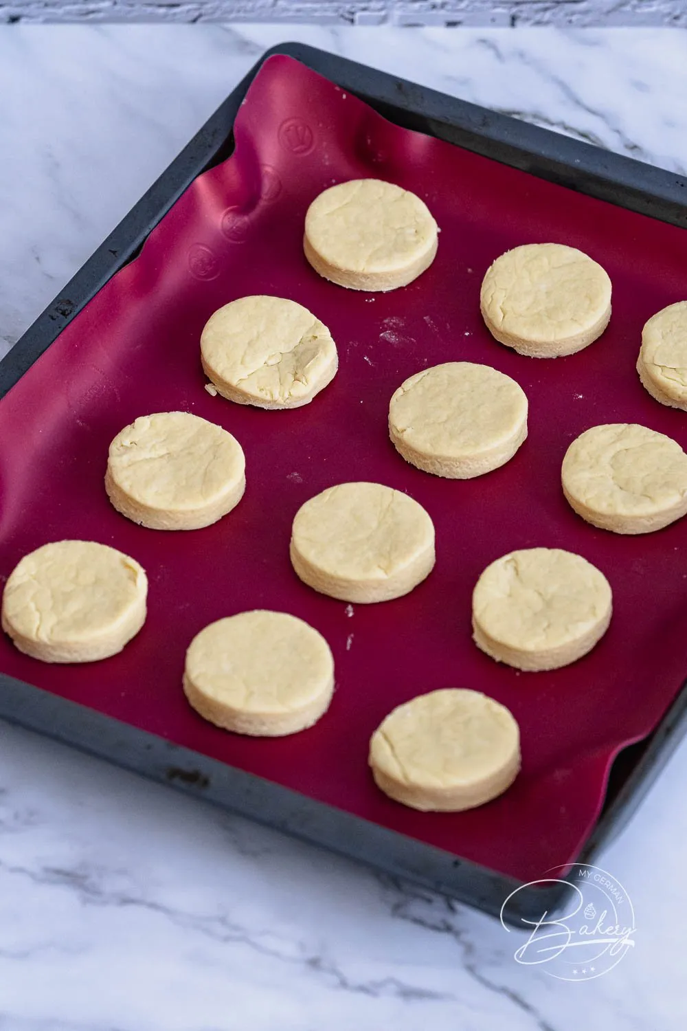Ausgestochene Scones-Teiglinge auf einem mit Backpapier ausgelegten Backblech, bereit zum Bestreichen