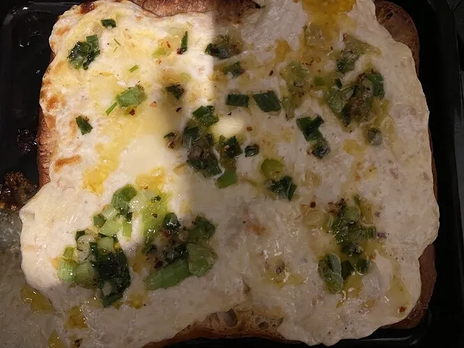 Beträufeln des gebackenen Käse-Toasts mit würziger Butter