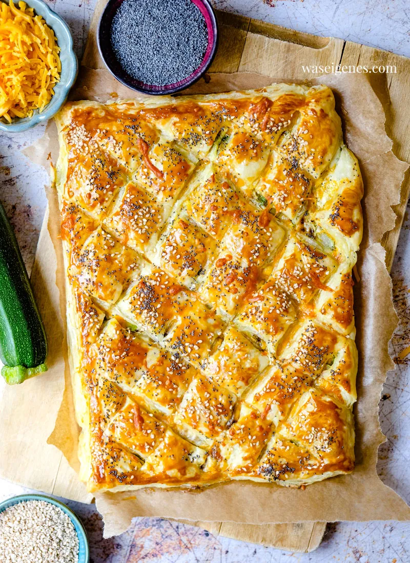 Blätterteig-Zupfbrot mit Zucchini und Cheddar auf einer Holzplatte, bereit zum Servieren