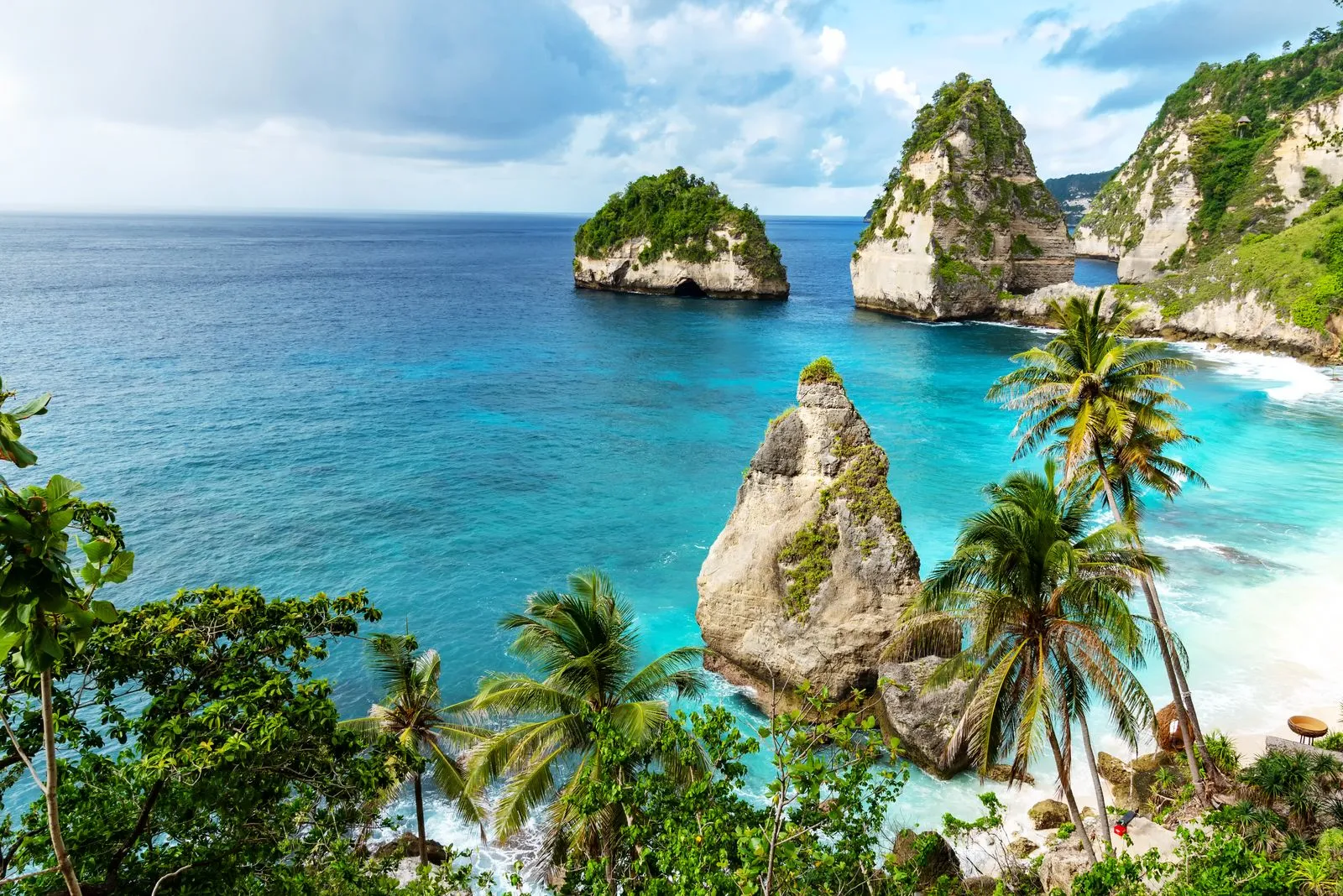 Blick auf einen tropischen Strand auf Bali mit türkisfarbenem Wasser und Palmen