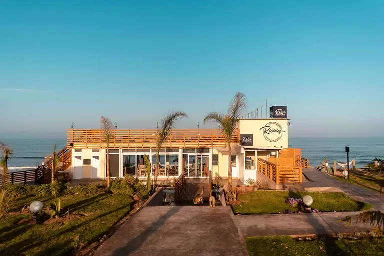 Blick auf Richies Beachclub am Strand mit bequemen Liegen und Himmelbetten unter marokkanischer Sonne