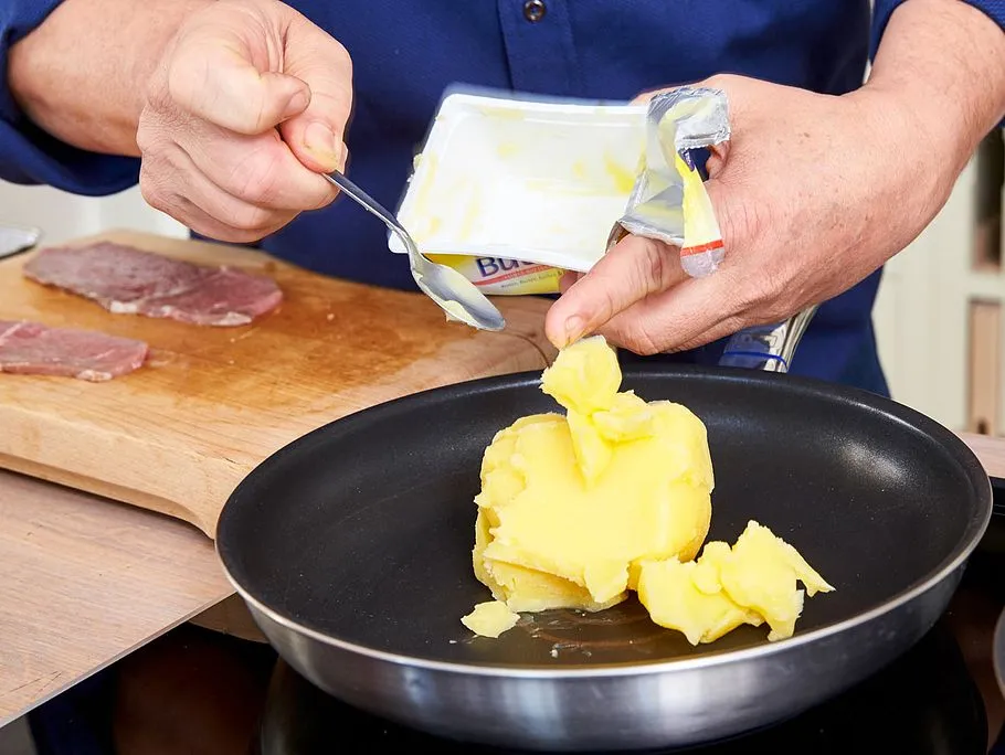 Butterschmalz schmilzt in einer heißen Pfanne und bildet eine glänzende Oberfläche.