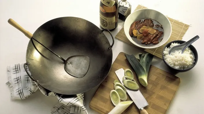 Chinesisches Geschirr mit Suppe, Reis und geschnittenem Lauch, symbolisch für die Vielfalt der Speisen.