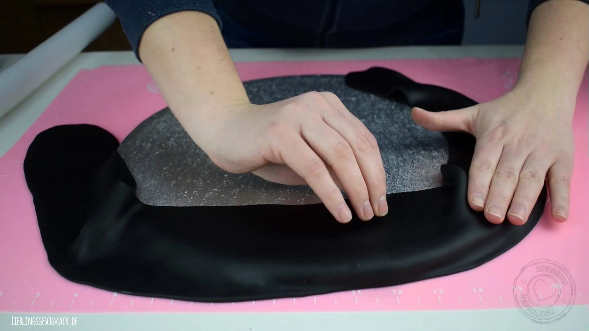 Das Cakeboard wird mit schwarzem Fondant bedeckt und mit weißen Streifen versehen, um eine Rennstrecke zu simulieren