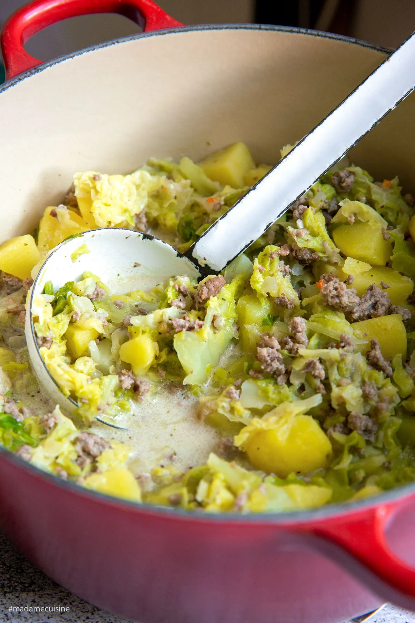 Der fertige Wirsing-Eintopf mit Hackfleisch und Kartoffeln, serviert in einer traditionellen Steinschale auf einem Holztisch