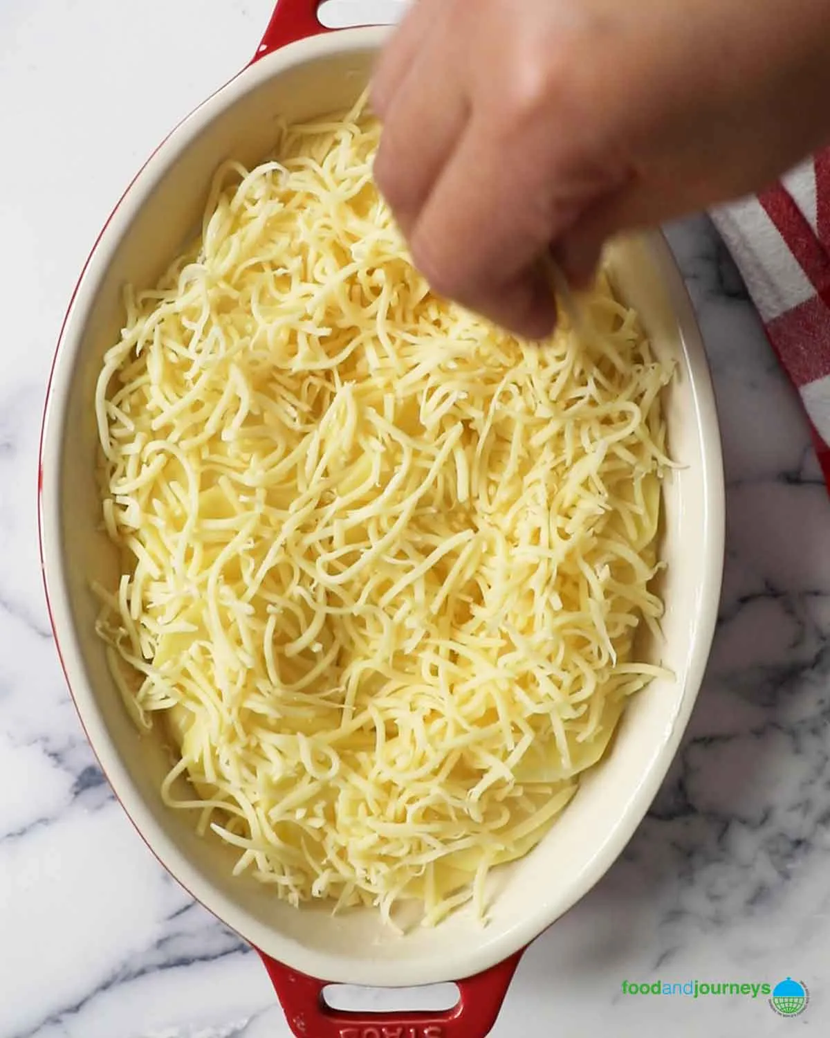 Der letzte Schritt bei der Kartoffelgratin-Zubereitung ist das Hinzufügen von geriebenem Käse, bevor es in den Ofen kommt.