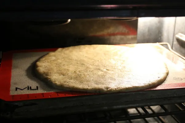 Der vorgebackene Pizzaboden auf einem umgedrehten Backblech