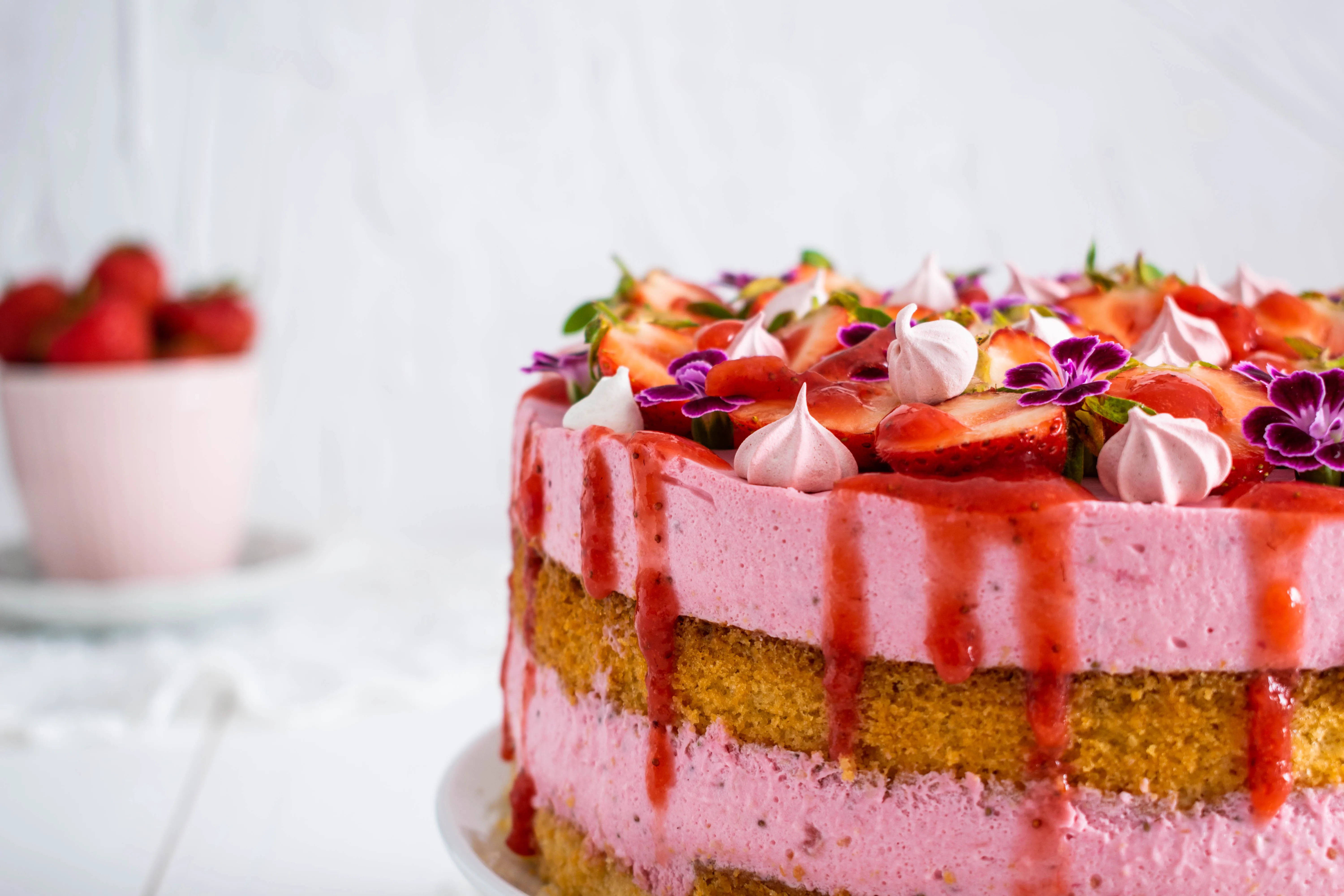 Detailansicht der Erdbeersahnetorte mit eleganter Blütendekoration, die die frische und leichte Süße unterstreicht