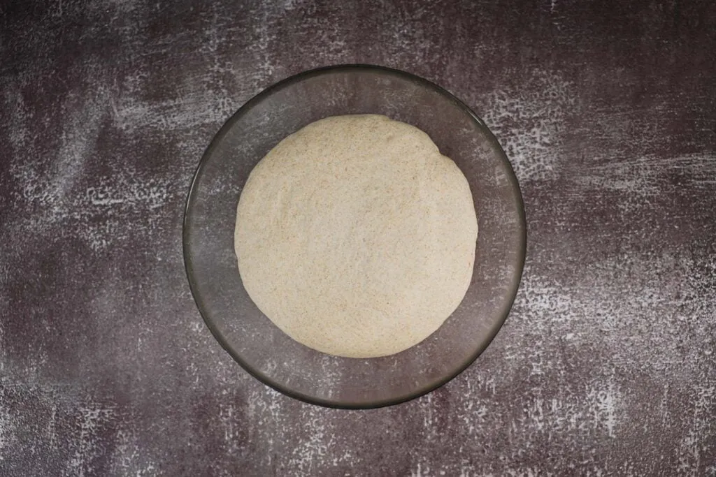 Detailaufnahme der rustikalen, knusprigen Kruste eines selbstgebackenen veganen Brotes, die Perfektion verspricht.