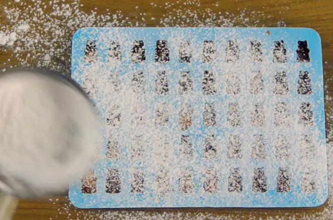 Die gefüllten Gummibärchen-Formen werden abgedeckt und gekühlt.