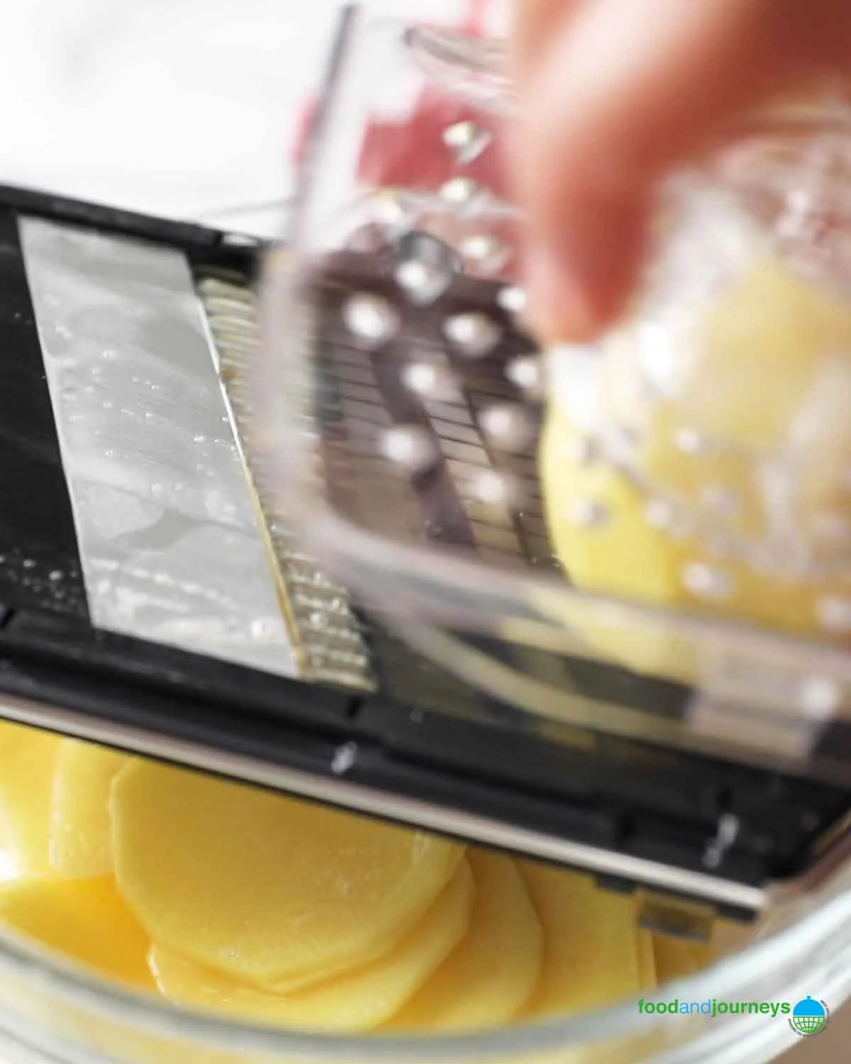 Dünne Kartoffelscheiben für deutsches Kartoffelgratin mit einer Mandoline herstellen.