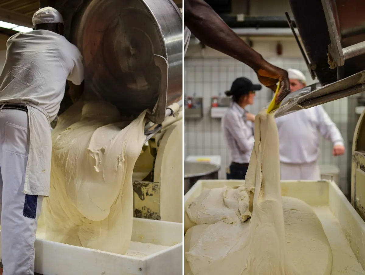 Ein Bäcker schabt Teig von einer Arbeitsfläche, ein alltäglicher Anblick in einer geschäftigen Bäckerei.