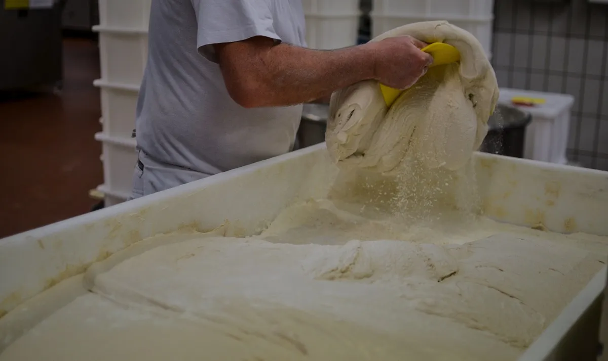 Ein Bäcker teilt Teig in gleichmäßige Portionen, ein wichtiger Schritt für die Konsistenz der Backwaren.