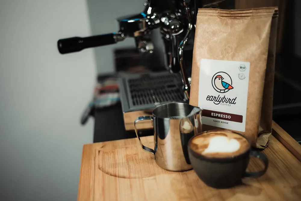 Ein Barista bereitet einen cremigen Cappuccino mit Latte Art an einer Siebträgermaschine zu.