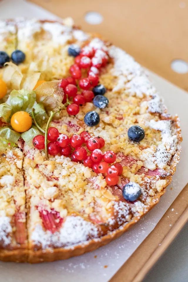 Ein bunter Obststreuselkuchen auf einem hellen Holzbrett, perfekt für eine Sommerkaffeetafel