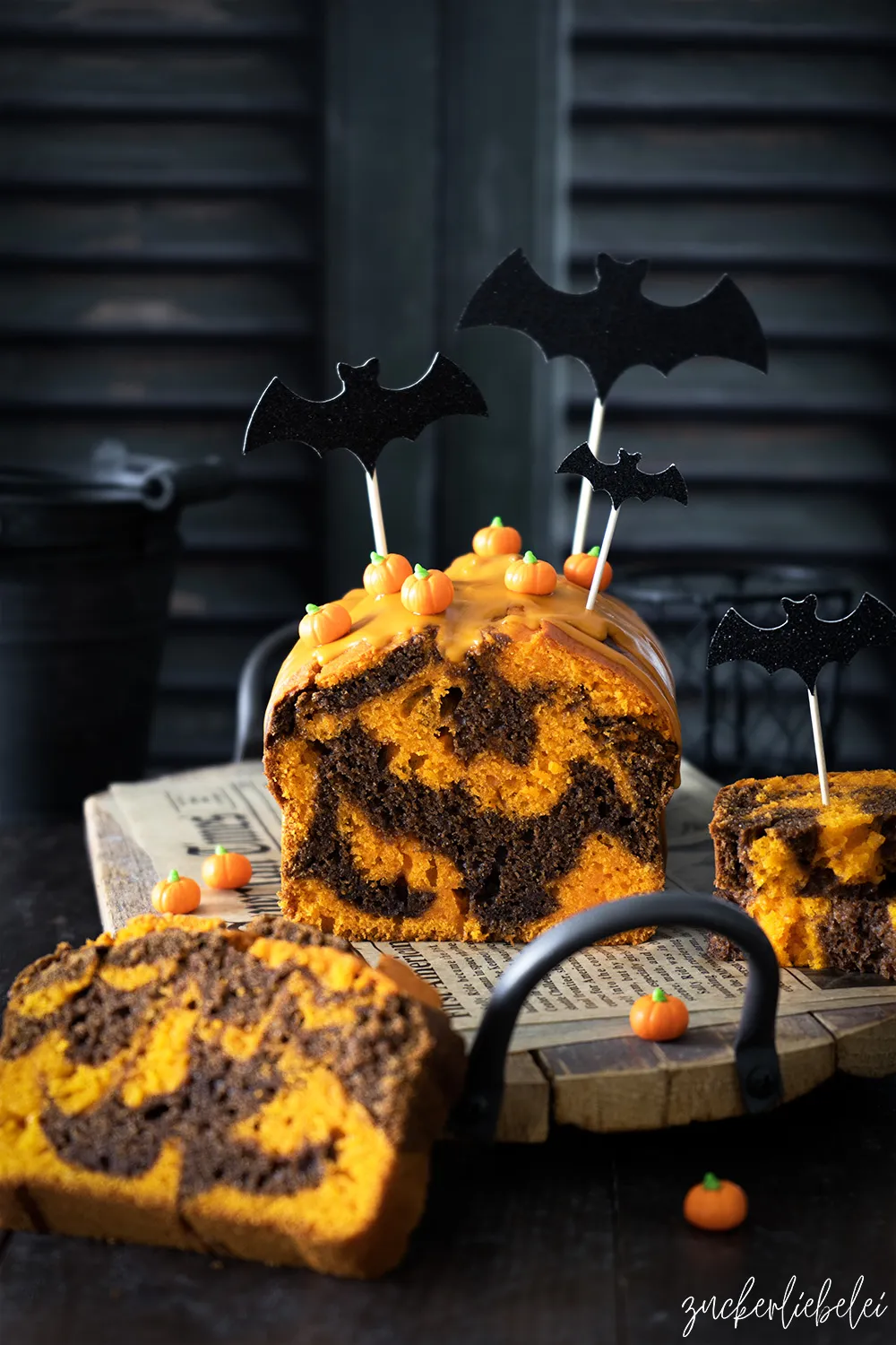 Ein dekorierter Halloween-Marmorkuchen mit Schokoladen- und Kürbisanteilen, der in einer Kastenform gebacken wurde und mit einem orangenen Guss überzogen ist.