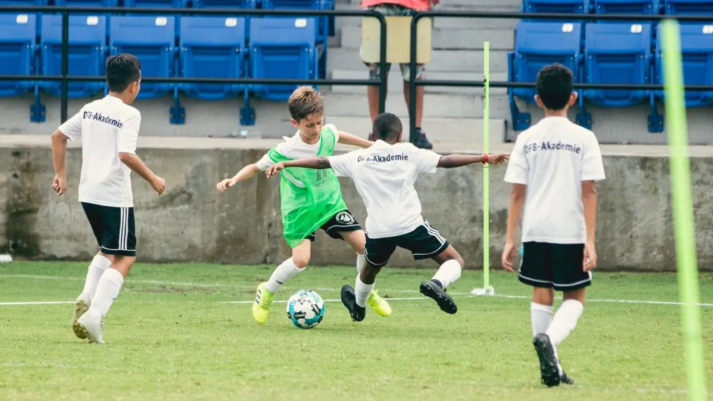 Ein DFB-Trainer gibt Anweisungen an eine Gruppe junger Spieler auf dem Trainingsfeld