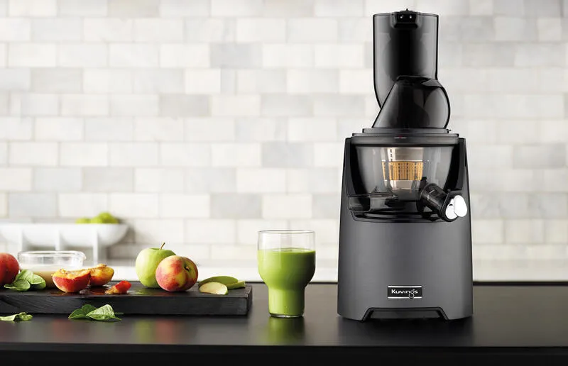 Ein eleganter Entsafter auf einer stilvollen Arbeitsplatte, umgeben von einer Schüssel frischer, saftiger Früchte.