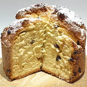 Ein frisch gebackener, goldbrauner Panettone mit Rosinen und Zitrusfrüchten, angeschnitten auf einem Holzbrett